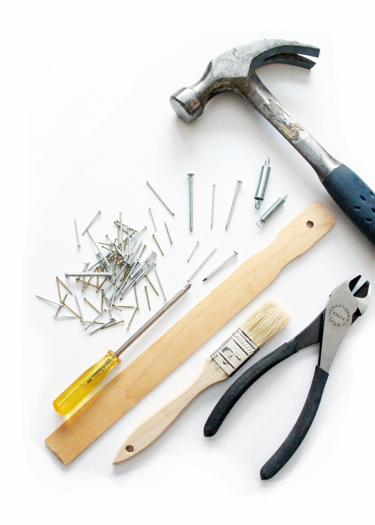 Hammer, nails, brush and pliers arranged for a repair job